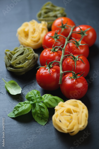 Branch of red tomatoes, coloured tagliatelle and green basil