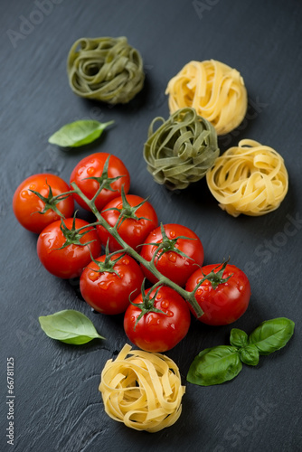 Branch of red tomatoes, tagliatelle and basil, high angle view