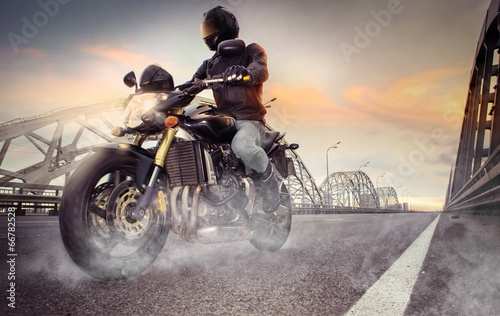 Man seat on the motorcycle on the city bridge