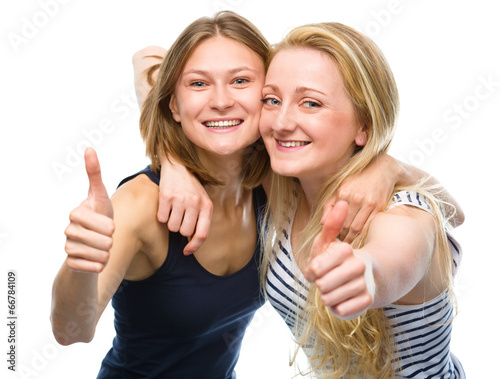 Two young happy women showing thumb up sign