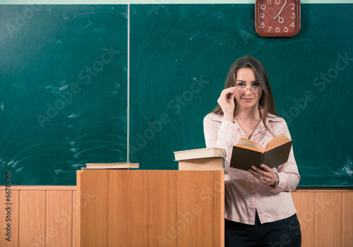 female teacher with open book at classroom