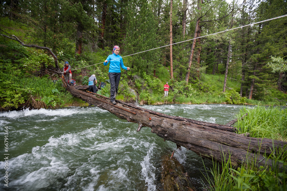 Backpackers are crossing mountain river by wooden log in Altai m Backpackers are crossing mountain river by wooden log in Altai m