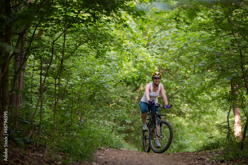 Woman is cycling in spring forest