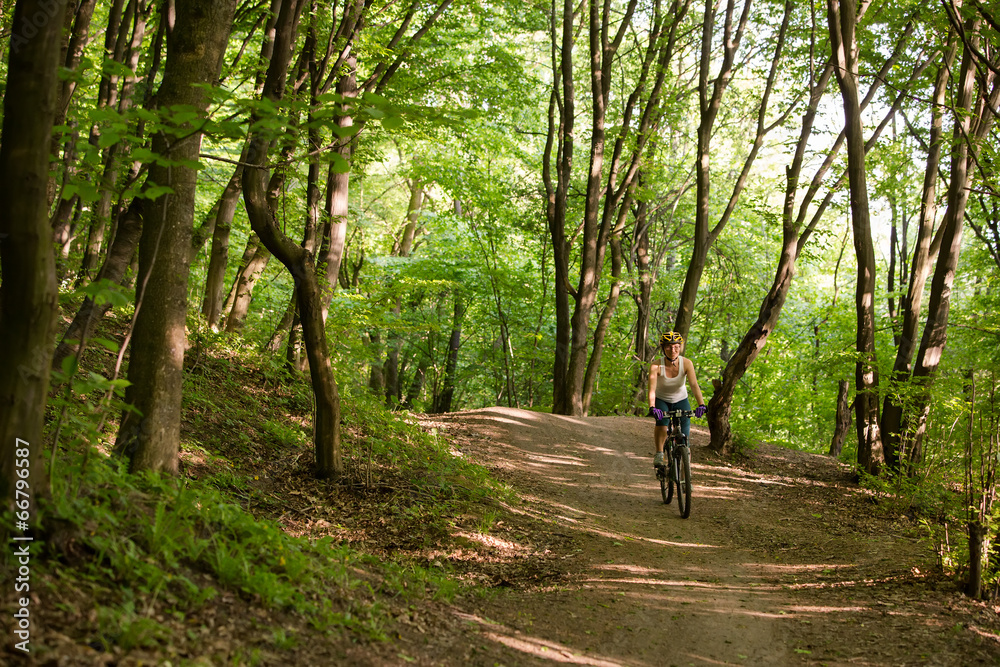 Woman is cycling in spring forest Woman is cycling in spring forest