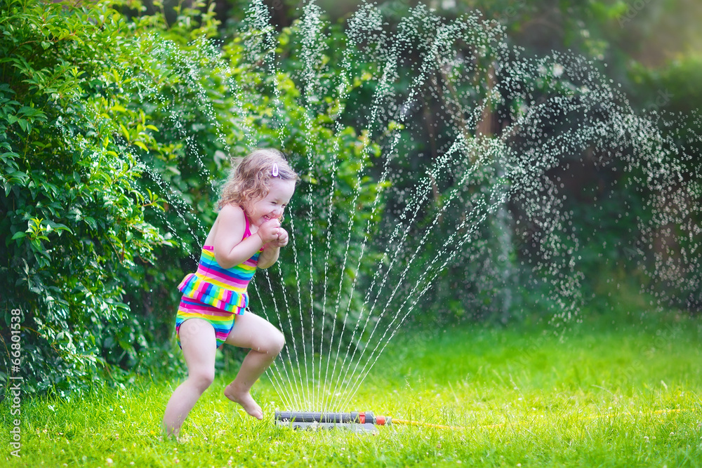 Little girl playing with garden sprinkler - obrazy, fototapety, plakaty 