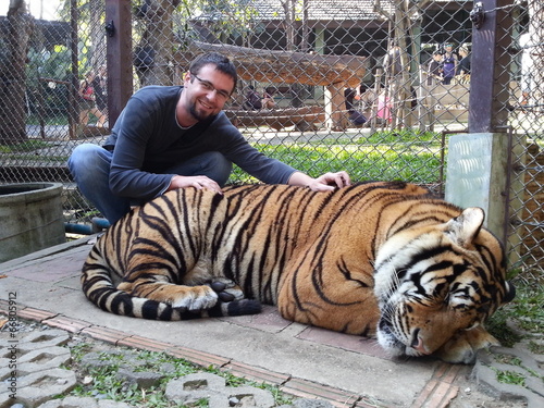 Young man cuddling live tiger