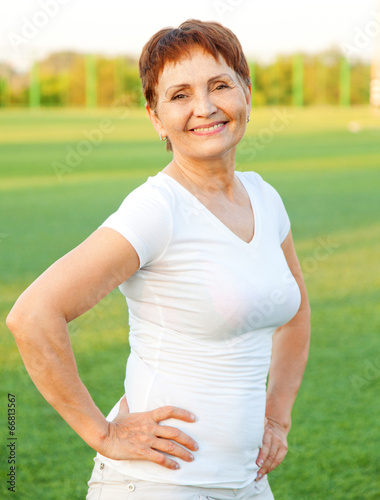 attractive woman 50 years in a white shirt on a background of gr