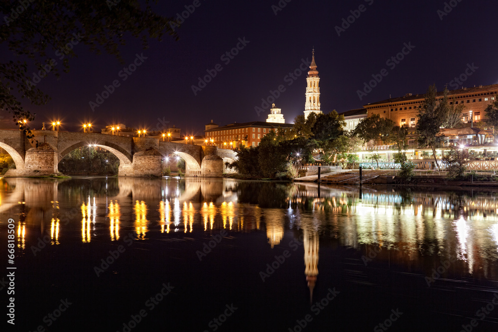  old stone bridge is reflected in river at night, Zaragosa