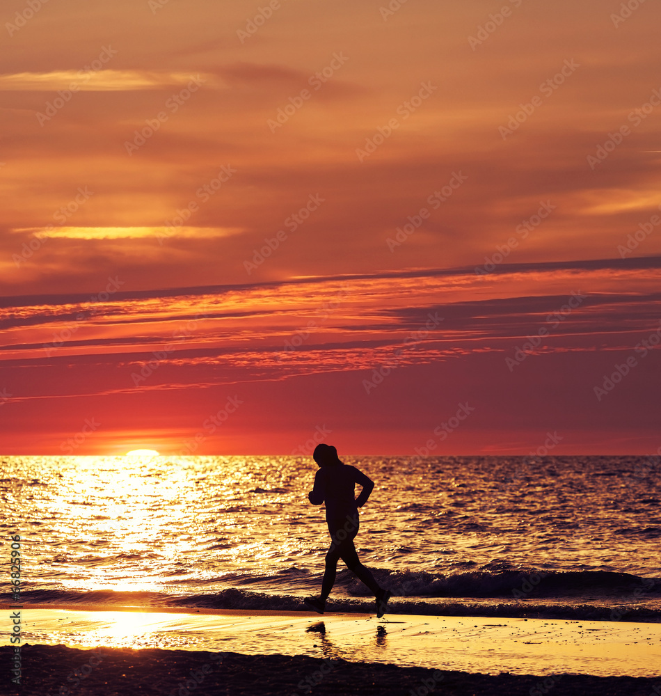 Woman running at beautiful sunset in the beach.