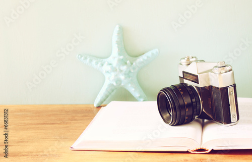 vintage camera, book and decorations over wooden shelf   photo