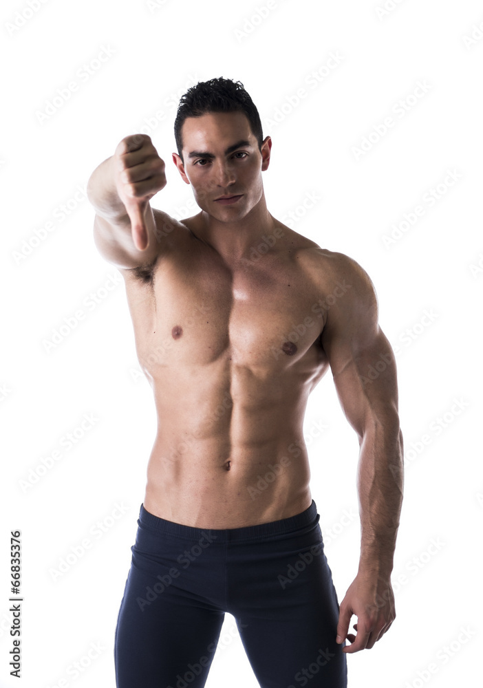 Disappointed muscular young man doing thumb down sign Disappointed muscular young man doing thumb down sign