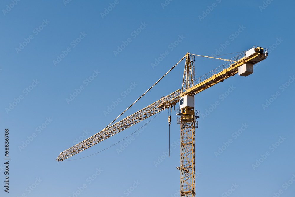 Ein gelber Baukran vor wolkenlosem blauen Himmel Ein gelber Baukran vor wolkenlosem blauen Himmel