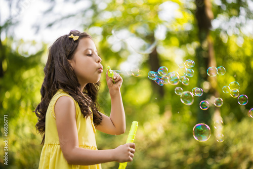 Little girl blowing soap bubble