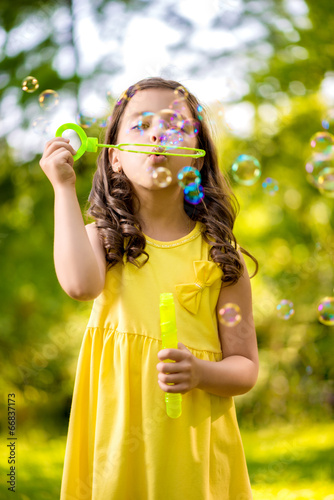 Little girl blowing soap bubble