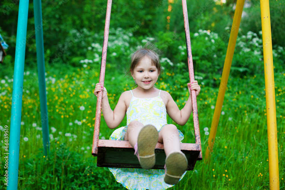 Little beautiful girl swinging in park