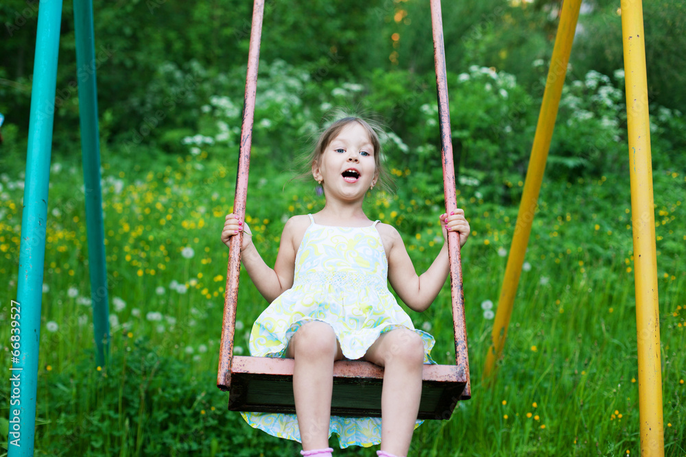 Little beautiful girl swinging in park