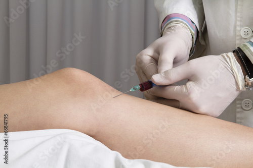 Fotografie Closeup of doctor injecting platelet rich plasma to knee