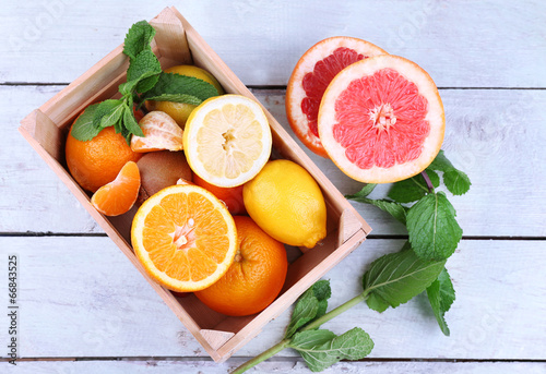 Slika na platnu Fresh citrus fruits with green leaves in wooden box
