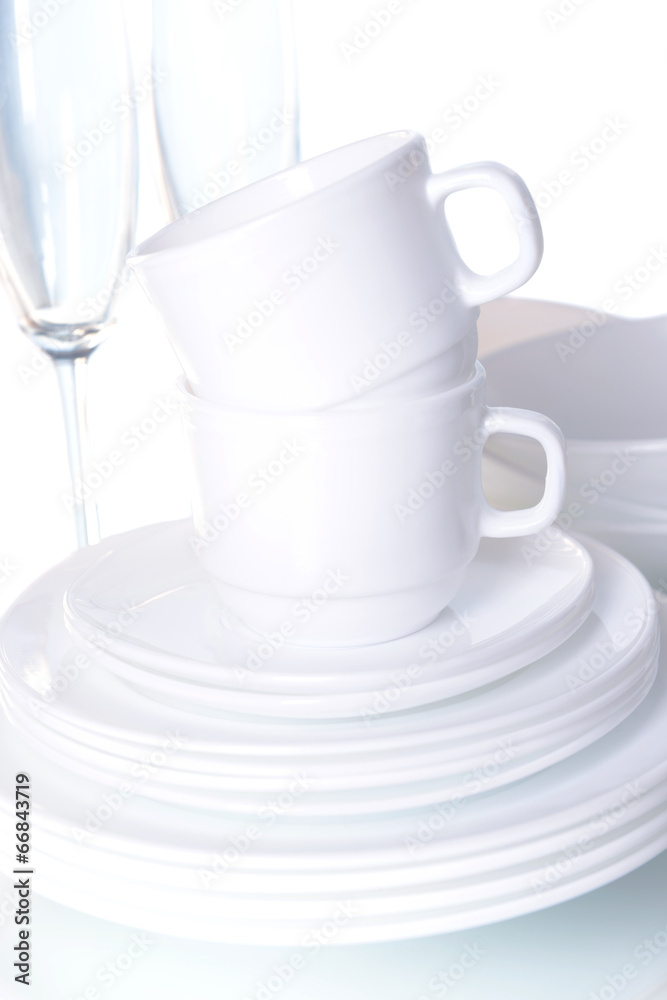 Set of white dishes on table on light background Set of white dishes on table on light background