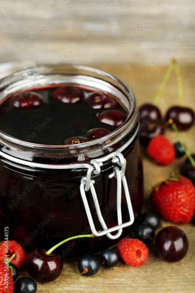 Tasty jam with berries in glass jar on wooden table Tasty jam with berries in glass jar on wooden table