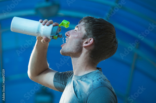 Fototapeta Naklejka Na Ścianę i Meble -  Athletic young man drinking water