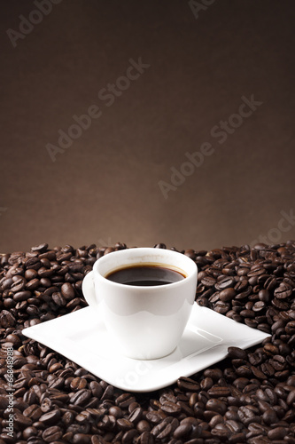 cup of coffee and coffee beans on brown background