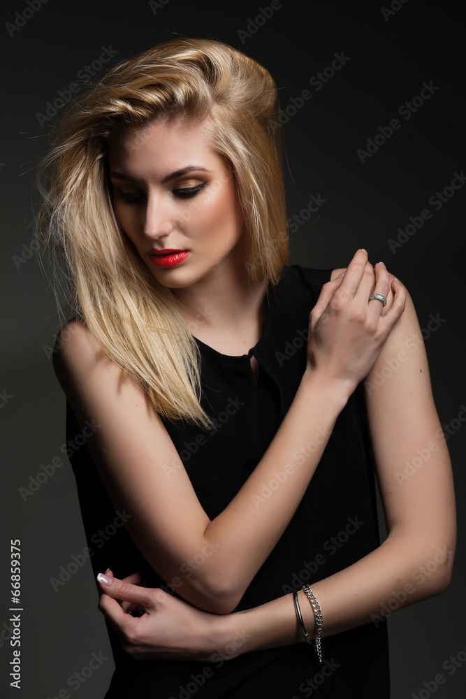 Fototapeta premium Beautiful blond woman with long hairstyle poses at studio