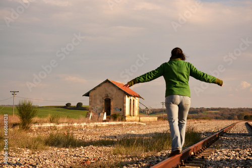 mujer haciendo equilibrio en las vias del tren photo