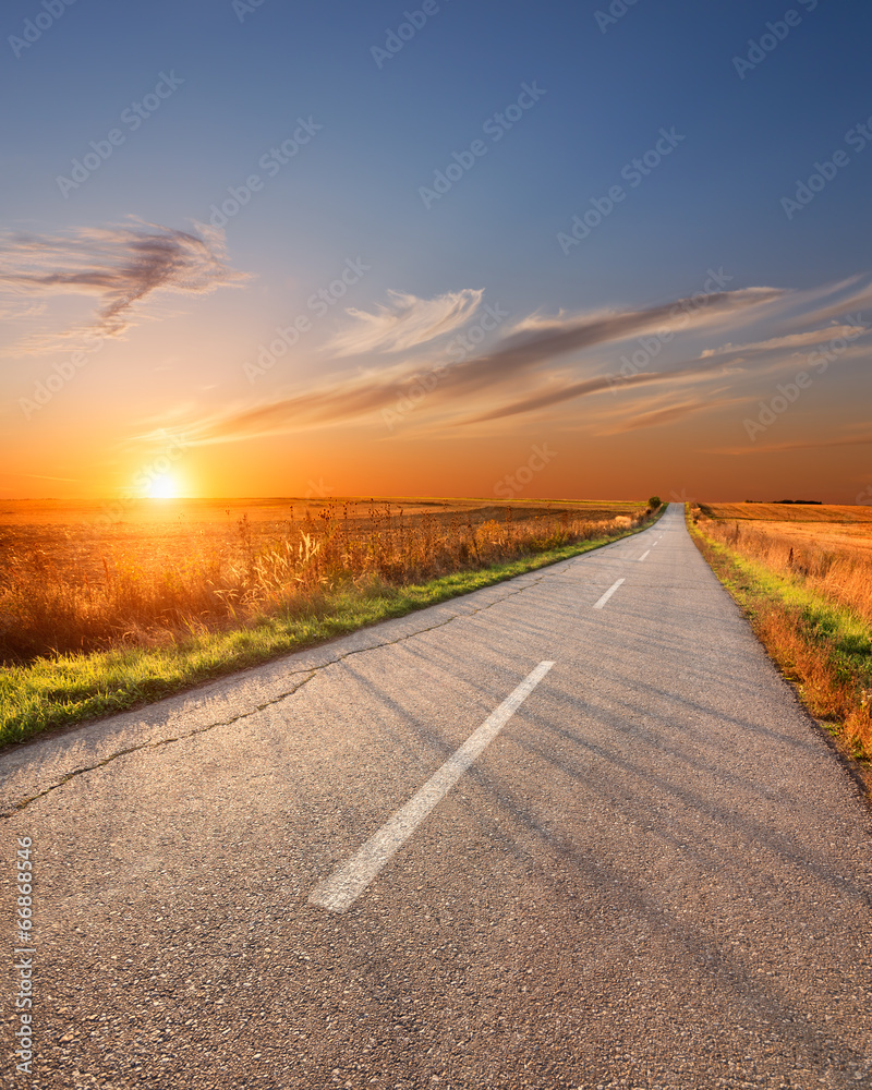 Obraz premium Driving on an empty aspalt road at sunset