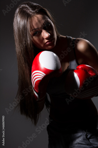 Girl with boxing gloves in front, bowed her head.