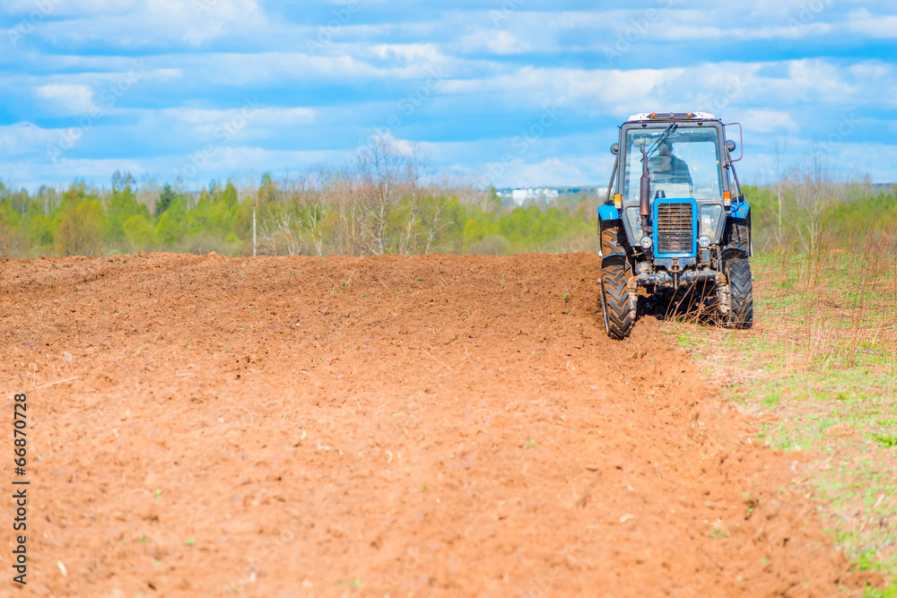 Obraz premium tractor plowed field in spring