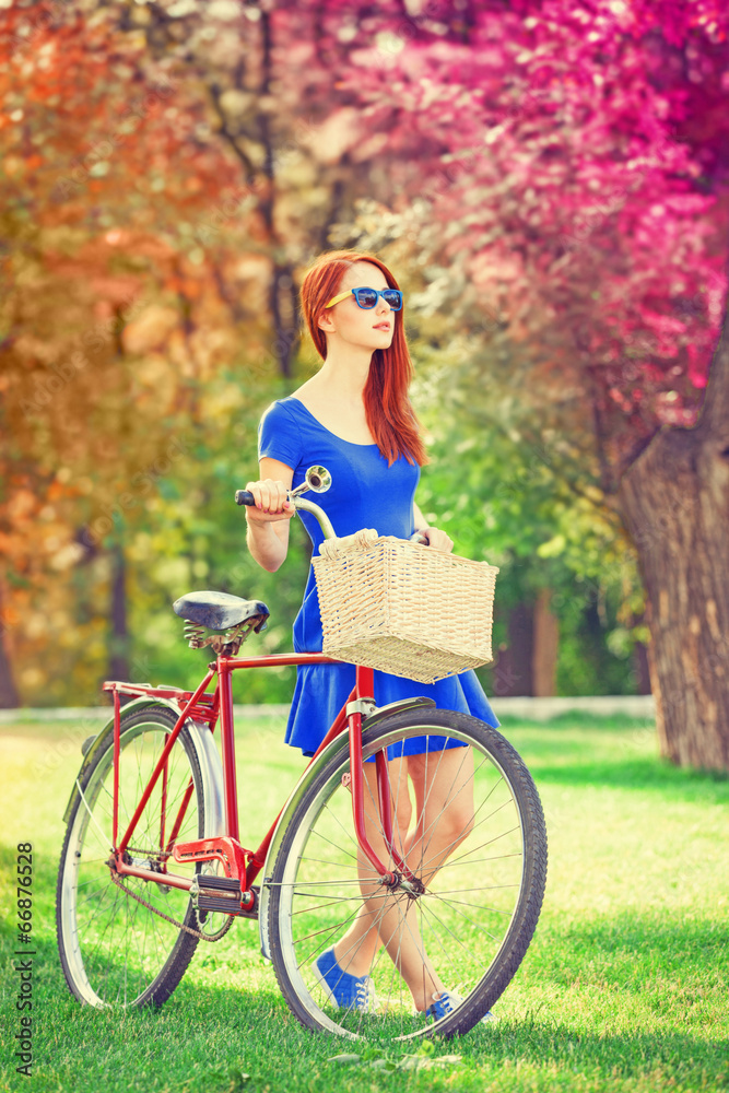 Redhead with bicycle in the park.