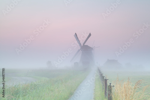 Dutch farmland with windmill in fog