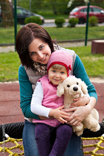 Mother and daughter with toy dog at bench