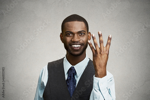 Smiling man giving four times gesture with hand grey background 