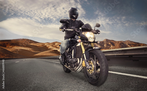 Man seat on the motorcycle on the desert road © vitaliy_melnik