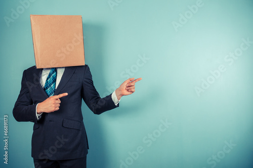 Businessman with box on head is pointing