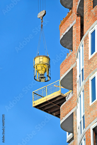 Crane lifting concrete mixer container on constructoin site photo