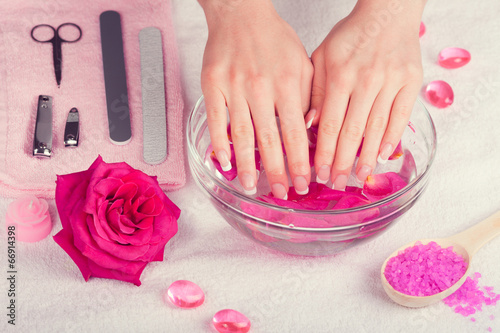 Beautiful woman's hands with french manicure in bowl of water