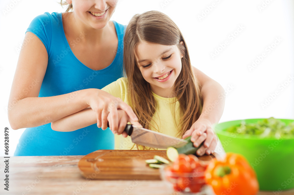 smiling little girl with mother chopping cucumber smiling little girl with mother chopping cucumber