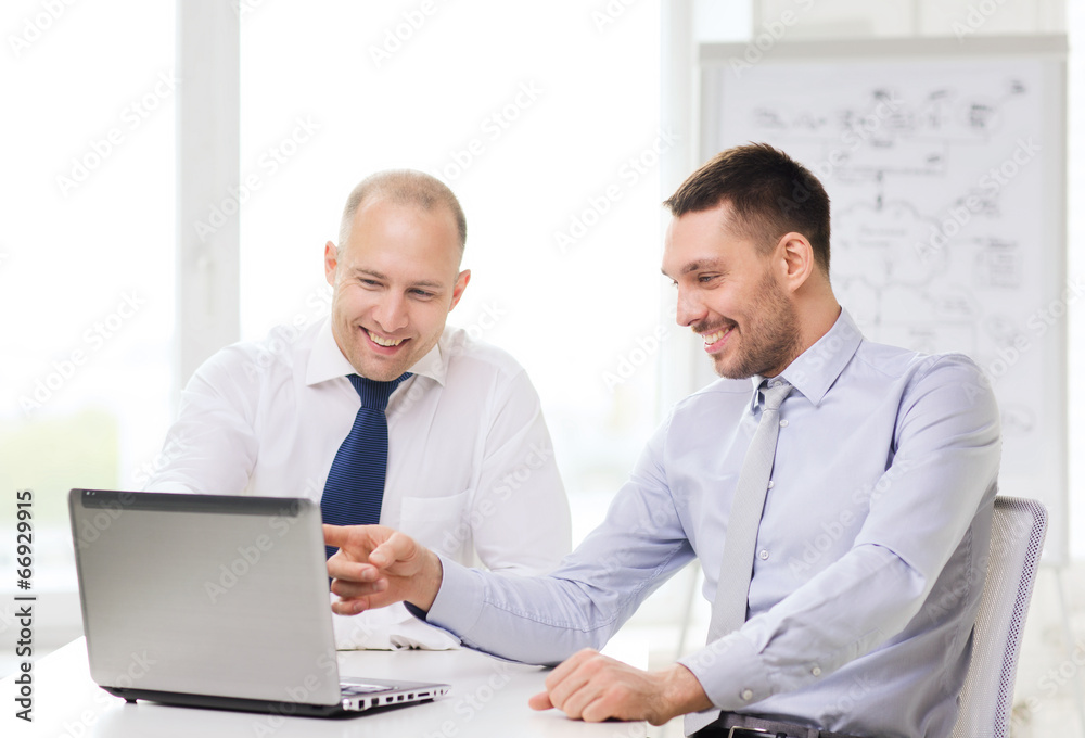 two smiling businessmen with laptop in office two smiling businessmen with laptop in office