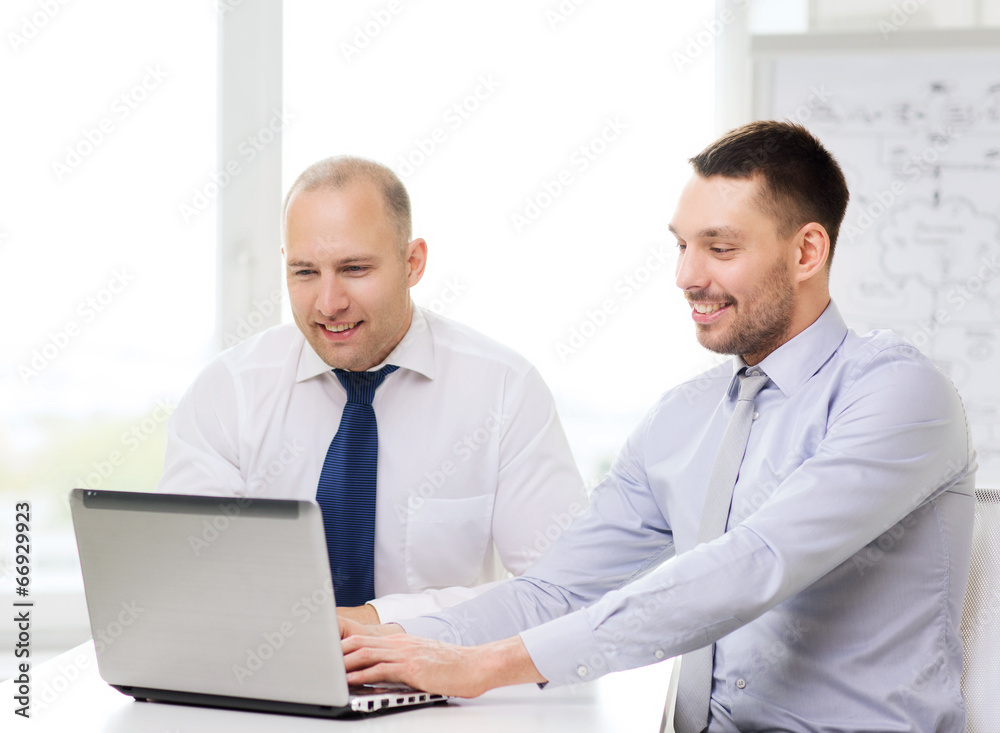 two smiling businessmen with laptop in office two smiling businessmen with laptop in office