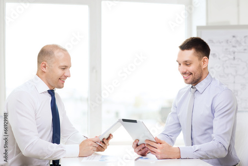 two smiling businessmen with tablet pc in office