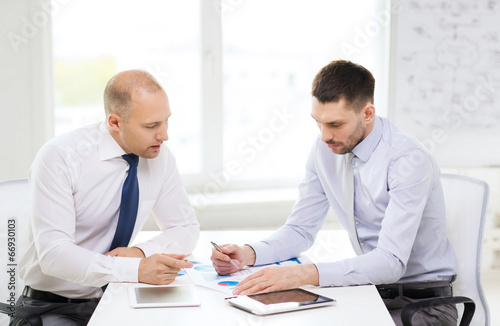 two serious businessmen with tablet pc in office