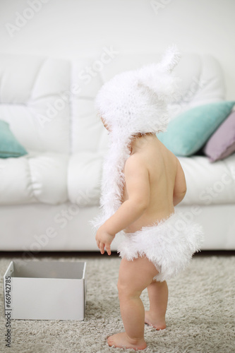 Back of barefoot baby in white soft hat and pants