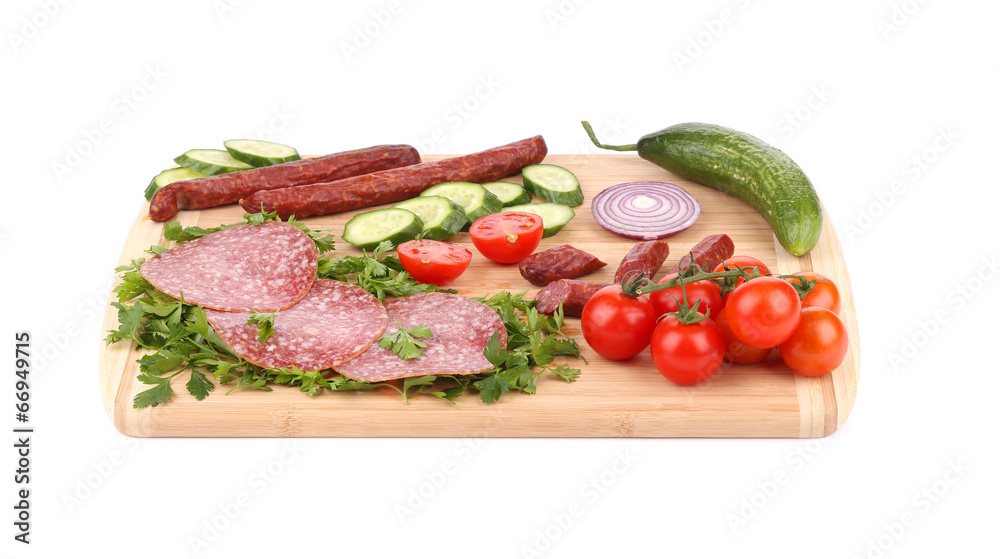 Sausage salami and vegetables on wooden platter. Sausage salami and vegetables on wooden platter.
