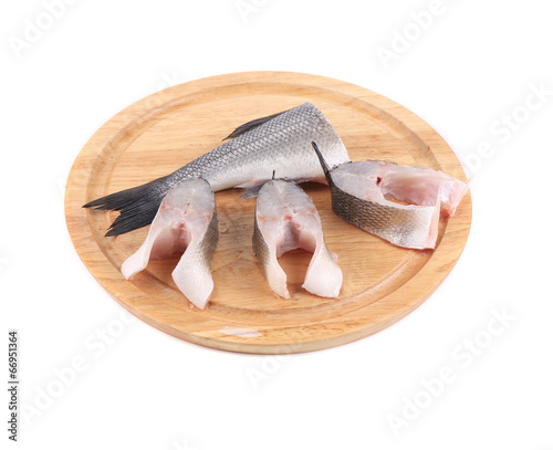 Canvas Print Steaks and tail of seabass on wooden platter.