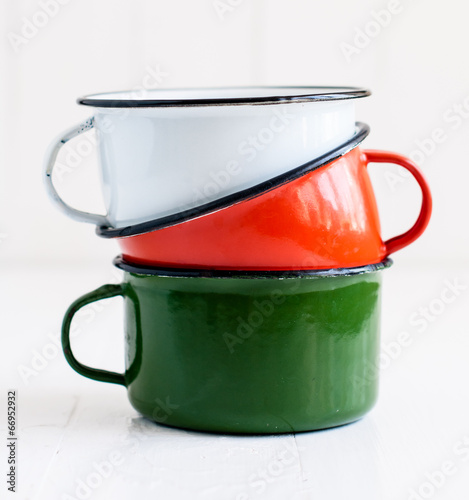 three bright colorful enameled mugs