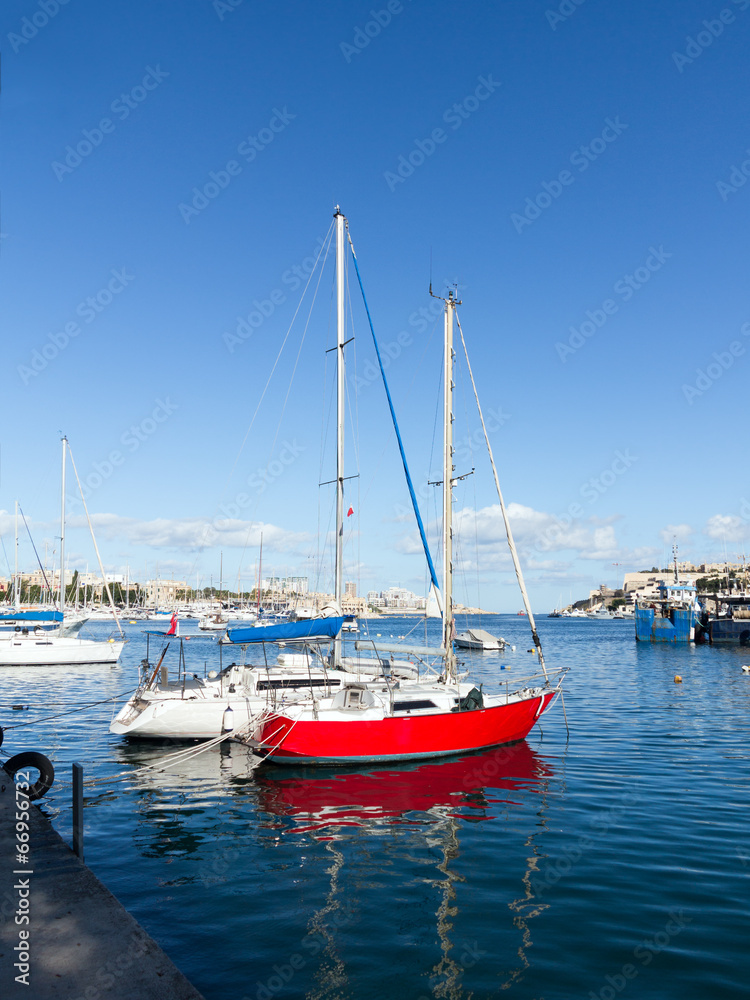 Maltese harbour with moored red sailing boat