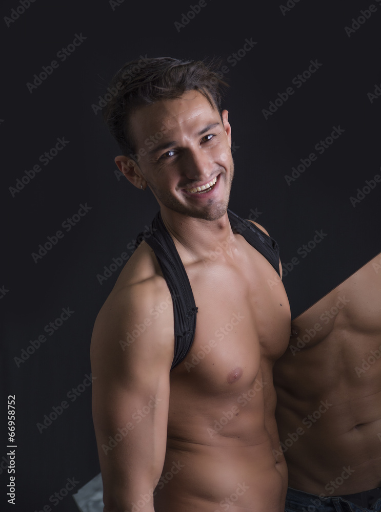 Smiling shirtless man holding mirror